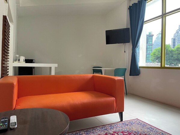 Una sala de estar moderna con sofá, una mesa de centro, televisor y una ventana con cortinas.