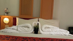 A neatly made bed with white linens, a red decorative runner, and two swan-shaped towels on the pillows. - Happy 2 Hotel Pratunam (Bangkok)