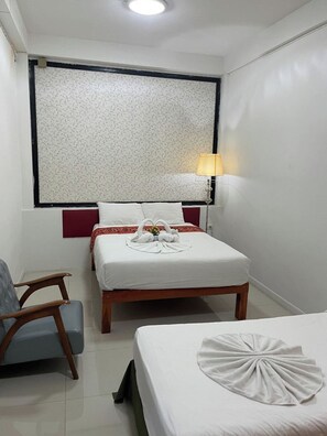 Una habitación de hotel con cama, una silla, una mesita de noche y una lámpara.