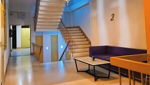 A modern interior with a staircase, a purple sofa, and a table with a globe ornament. - Happy 2 Hotel Pratunam (Bangkok)