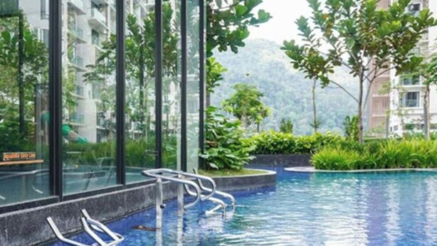 Ein Pool mit klarem, blauem Wasser, umgeben von üppiger Vegetation und modernen Gebäuden.