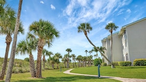 A pathway leading to a building with palm trees and a clear sky. - CP 134 Ocean View Condo - Vacation Rental in Ocean Village (Fort Pierce)