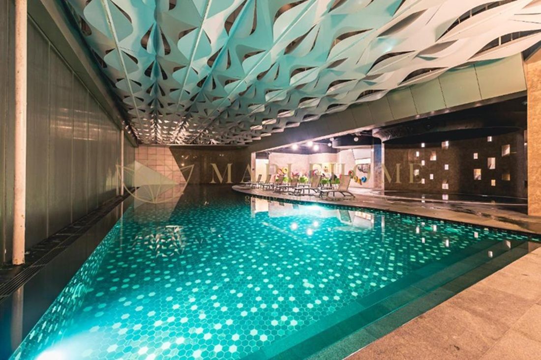 An indoor swimming pool with a geometric ceiling design and a tiled floor.