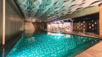 An indoor swimming pool with a geometric ceiling design and a tiled floor.