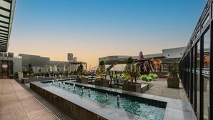 A rooftop pool area with a long rectangular pool, surrounded by potted plants and seating areas. - Ion Delemon Premier Suites Genting Highlands (Genting Highlands)