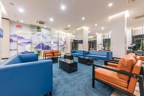 Un moderno vestíbulo con sofás azules, sillas de cuero naranja y una alfombra azul.