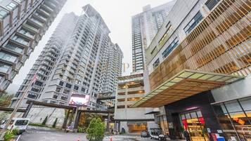 A modern urban hotel with high-rise buildings, a covered parking area, and a visible entrance.