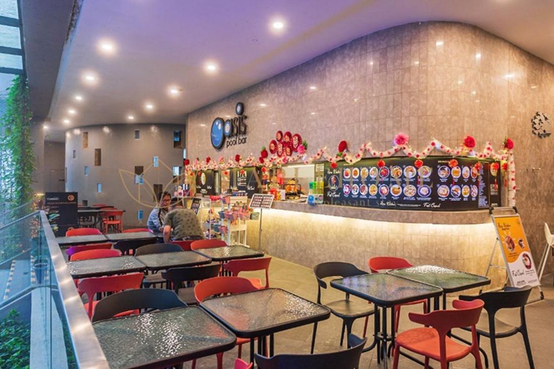 A pool bar with a curved counter, menu boards, and red chairs.