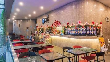 A pool bar with a curved counter, menu boards, and red chairs.