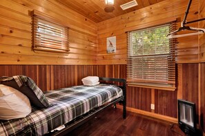 A wooden cabin room with a bed, a hanging light fixture, and a poster on the wall. - Silvertip Pines #2335 (Big Bear Lake)