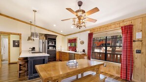 A kitchen with a central island, wooden cabinets, a microwave, and a ceiling fan.