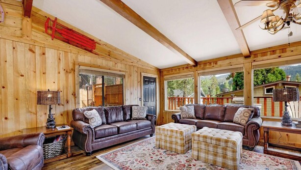 A cozy cabin interior with a leather sofa, ottoman set, and a patterned rug.