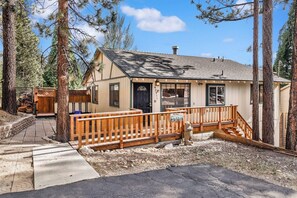 A small cabin with a wooden deck, a front door, and a mailbox. - Happy Bear #2053 (Big Bear Lake)