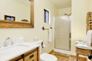 A bathroom with a white sink, a toilet, a shower with a glass door, and a wooden vanity. - Happy Bear #2053 (Big Bear Lake)