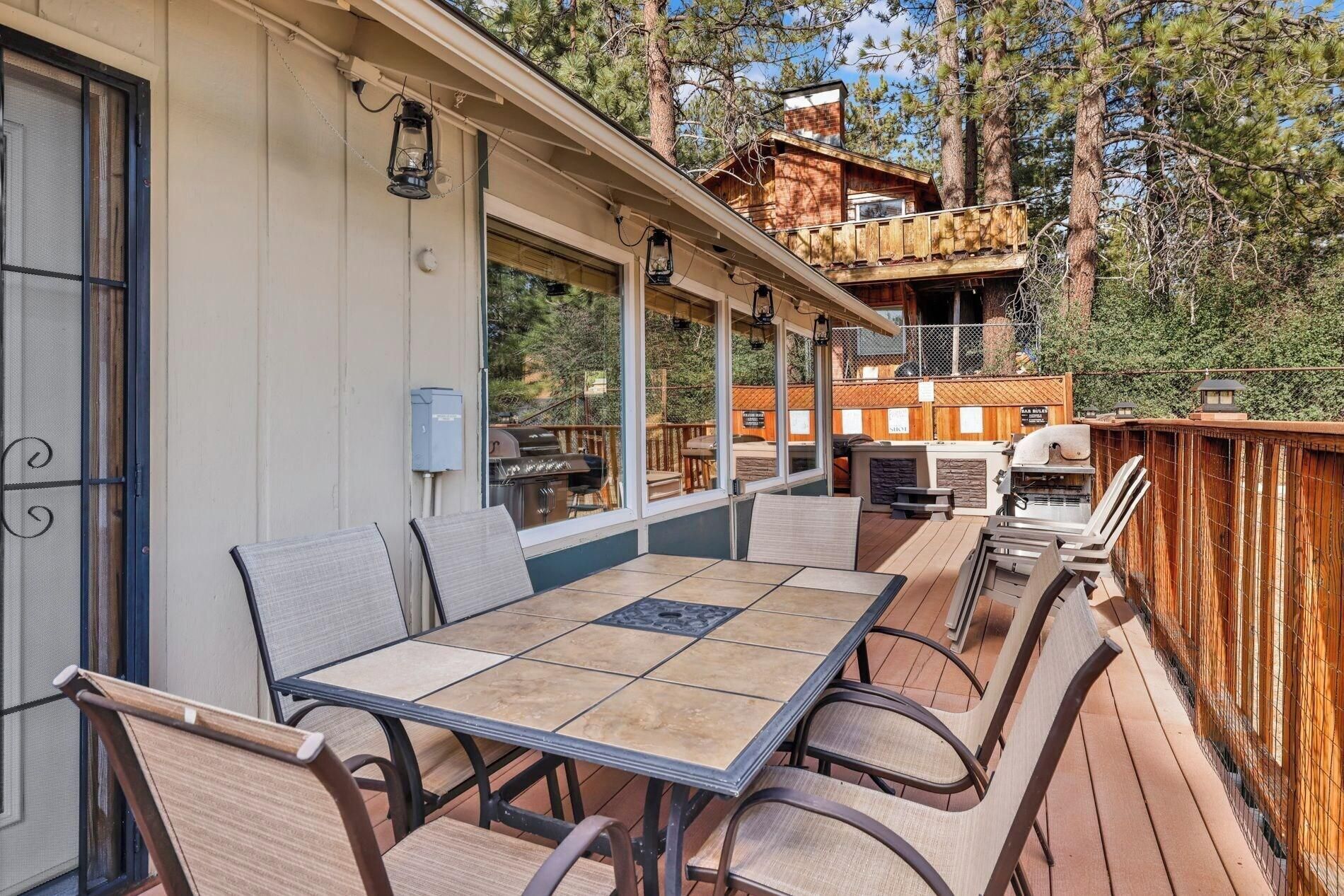 Un patio exterior cubierto con mesa y sillas, una parrilla y una terraza de madera.