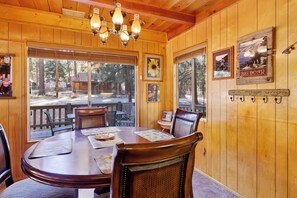 A wooden interior with a round dining table, chairs, and a chandelier. - Paradise In Cedar #2095 (Big Bear Lake)