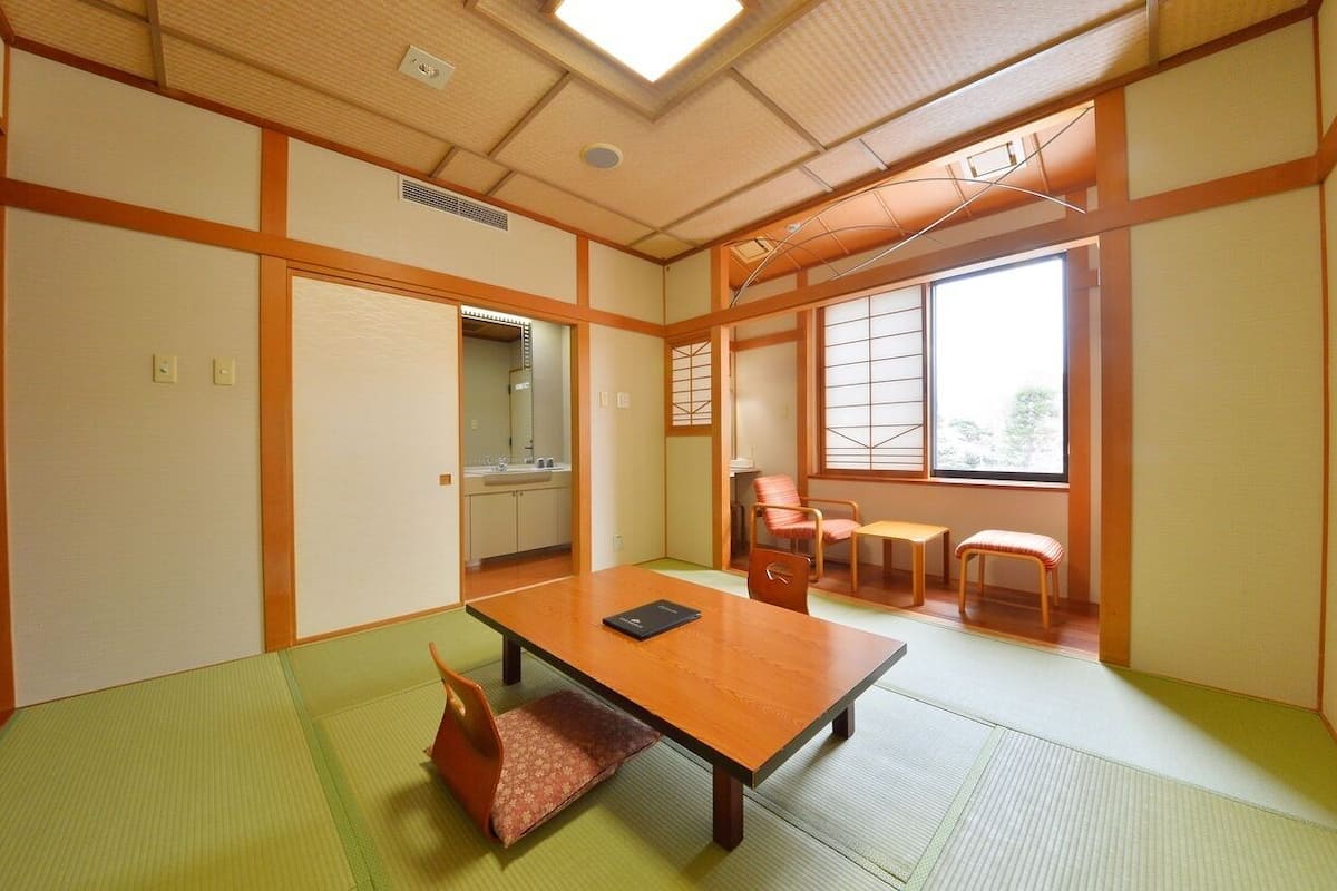 A traditional Japanese room with tatami flooring, a low table, and sliding doors.