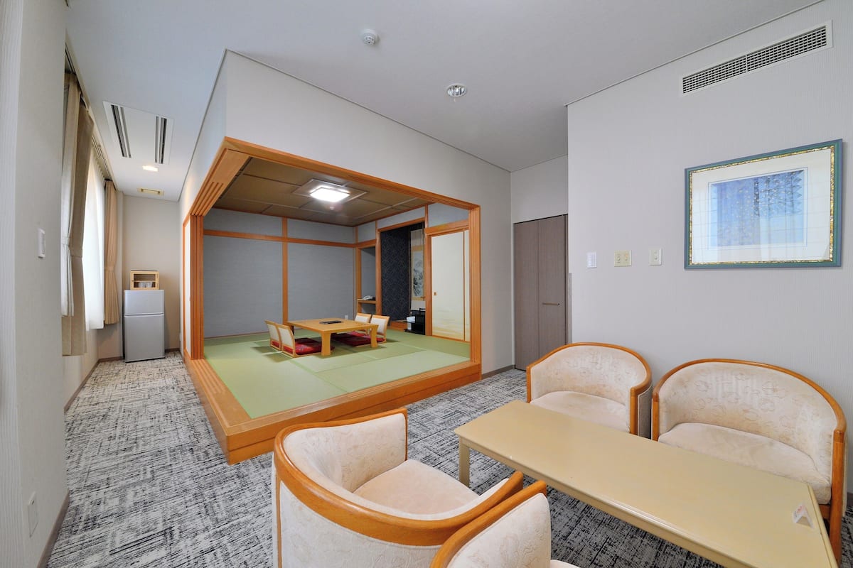 A traditional Japanese room with tatami flooring, a low table, and two tatami mat chairs.