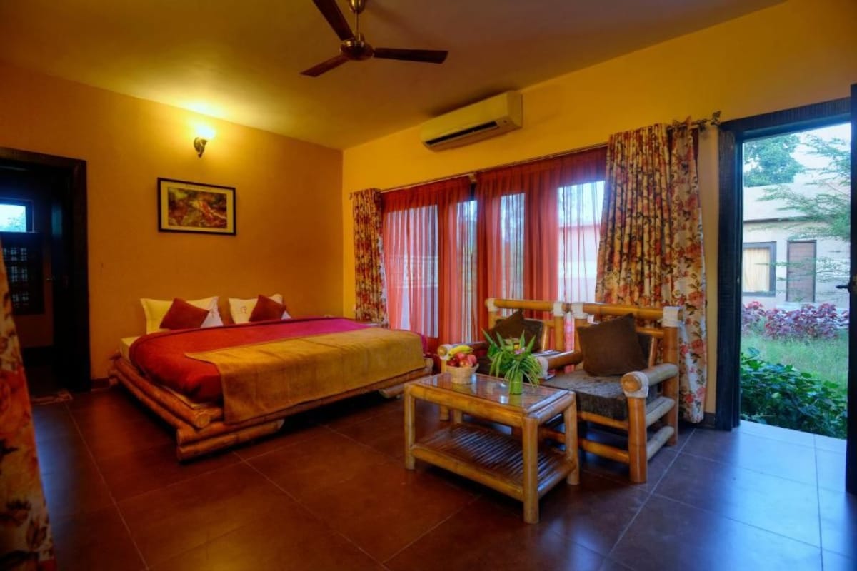 A room with a bed, a chair, a table, and a ceiling fan.