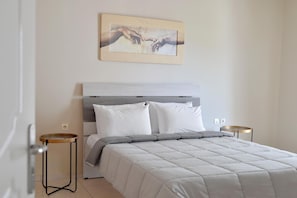 A bedroom with a bed, a headboard, two bedside tables, and a wall-mounted artwork.