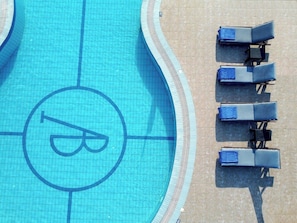 A swimming pool with lounge chairs and a logo on the water.