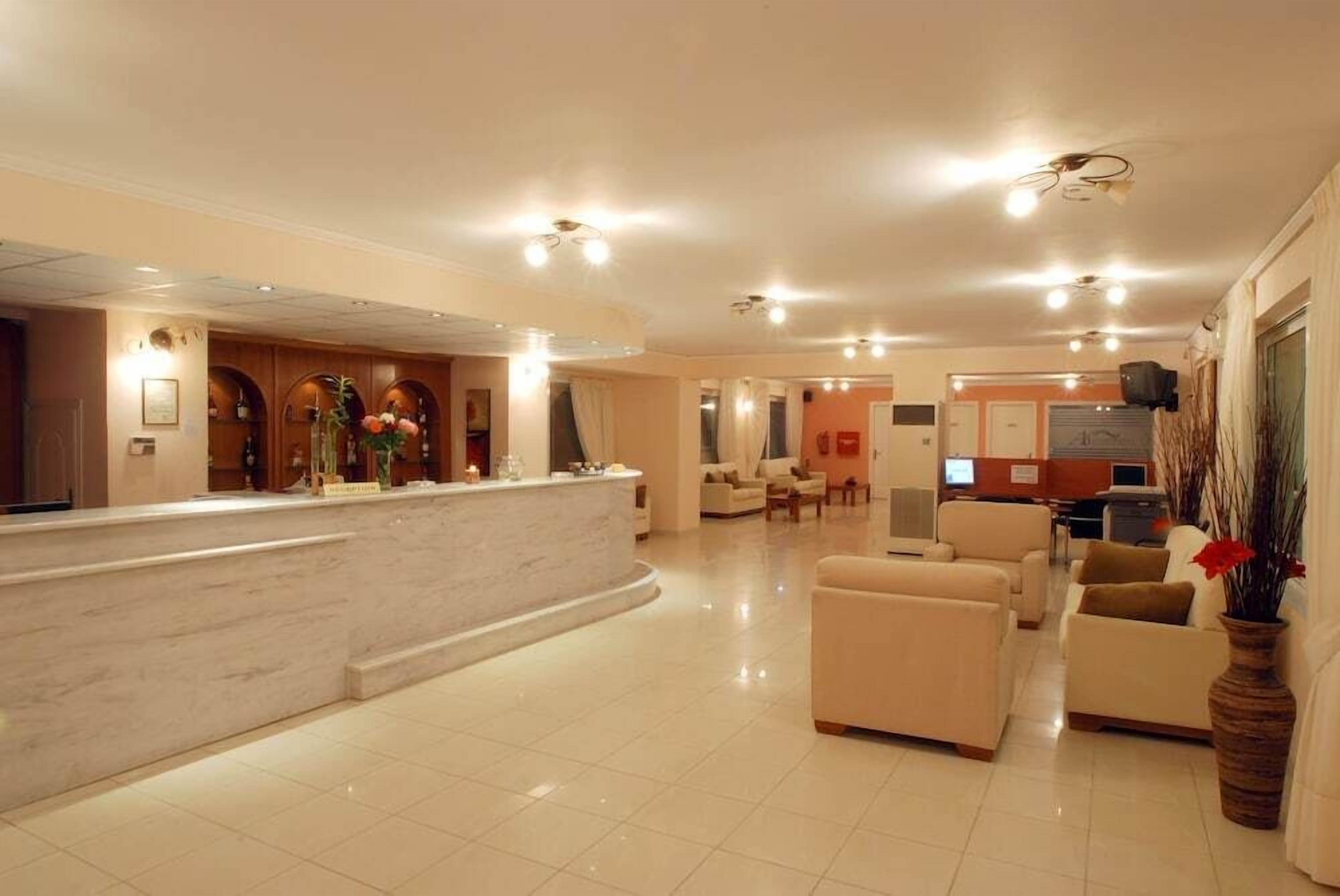 A hotel lobby with a reception desk, seating area, and a television.