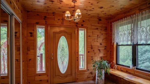 A wooden interior with a large door, a bench, and a potted plant. - Secluded 4-bedroom log cabin surrounded by beautiful forest (New Lisbon)