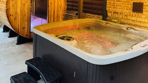 A spa area with a wooden sauna, a hot tub, and wooden benches. - Secluded 4-bedroom log cabin surrounded by beautiful forest (New Lisbon)