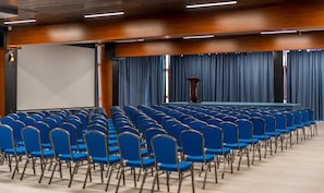 A conference room with rows of blue chairs, a podium, and a large screen. - Litz Resort Batumi (Batumi)