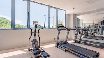 A gym with treadmills, an elliptical, and a mirrored wall.