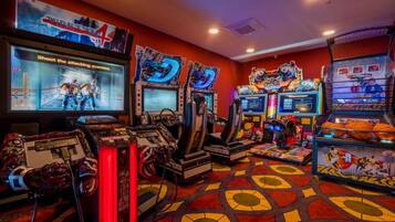 A gaming arcade with multiple arcade machines, a large screen displaying a game, and a basketball-themed display case.