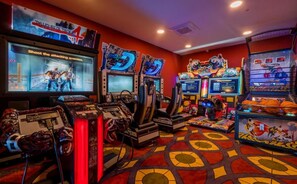 Une salle d’arcade dotée de nombreuses bornes d’arcade, d’un grand écran diffusant un jeu et d’une vitrine à thème sur le basketball.