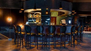 A bar area with a circular bar counter, multiple bar stools, and overhead lighting. - Litz Resort Batumi (Batumi)