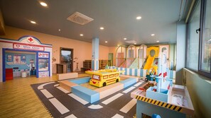 A children's play area with a yellow play bus, a mini clinic, and colorful play structures. - Litz Resort Batumi (Batumi)