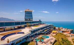 A hotel with a large pool, multiple levels, and a view of the ocean.