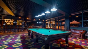 A pool table in a room with a patterned carpet, a bar area, and a leather couch. - Litz Resort Batumi (Batumi)