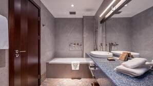 A modern bathroom with a wooden door, a bathtub, a sink, and a large mirror.