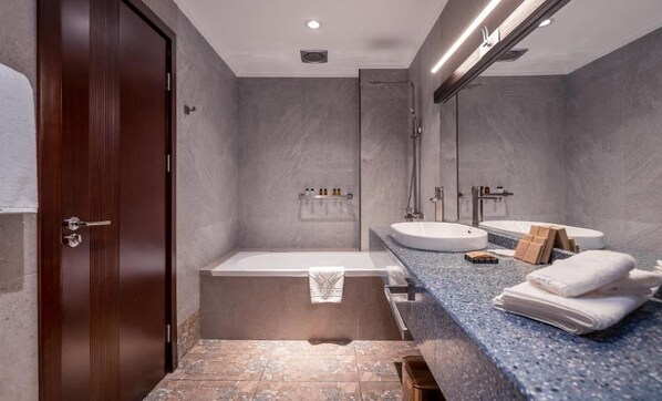 A modern bathroom with a wooden door, a bathtub, a sink, and a large mirror.