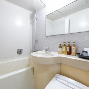 A bathroom with a white bathtub, a sink, a mirror, and a shower. There are toiletries on the sink counter.