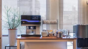 A coffee station with a coffee machine, a plant, and a glassware rack.