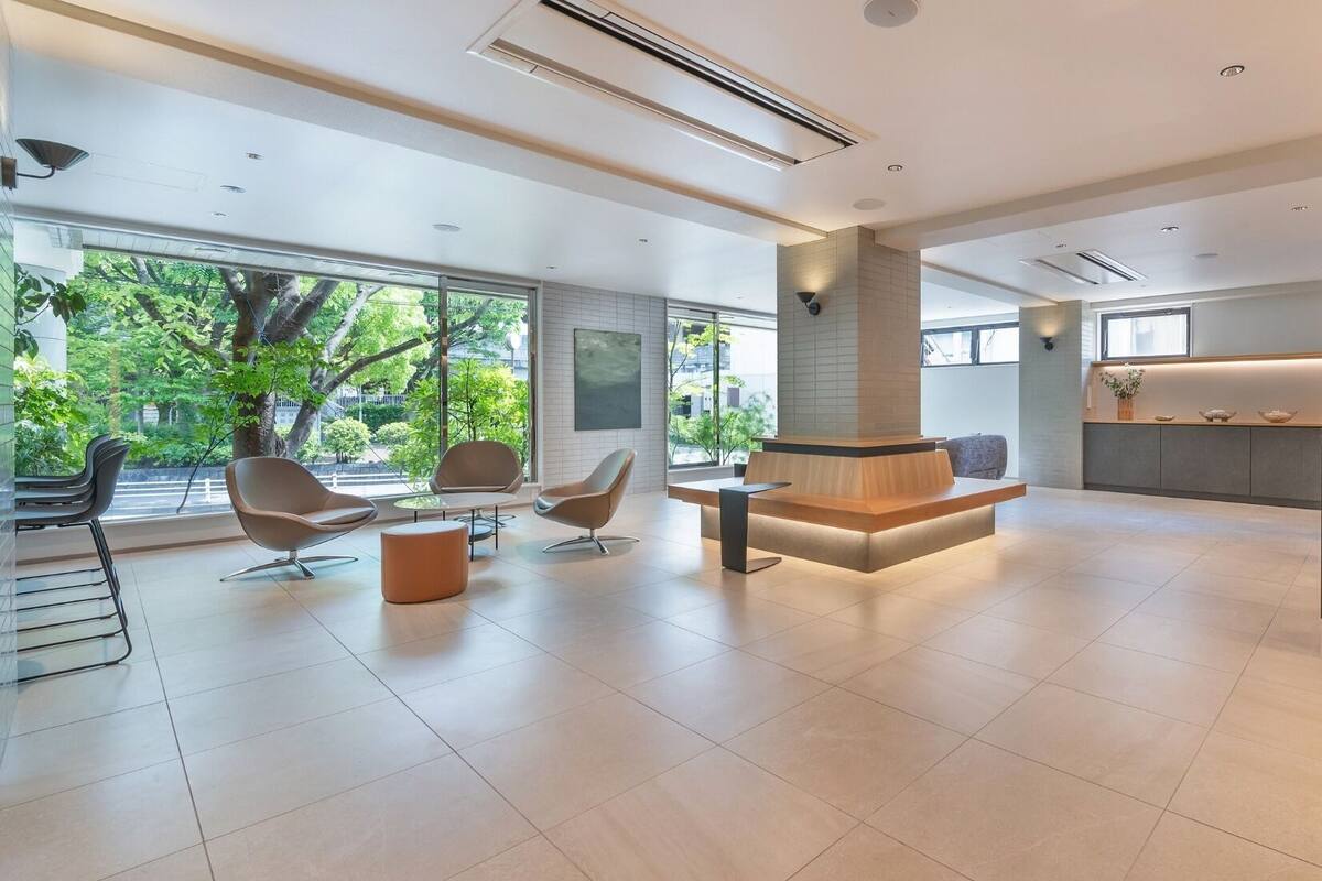 Un hall d’entrée moderne doté d’un espace salon central, d’un comptoir de réception et de grandes fenêtres donnant sur un paysage verdoyant.
