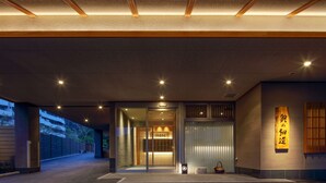 Una entrada moderna de edificio con una galería techada, un puerta corrediza de vidrio y un letrero tradicional japonés.