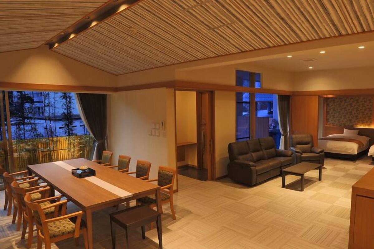 A spacious hotel room with a dining area, a sofa set, and a bed.