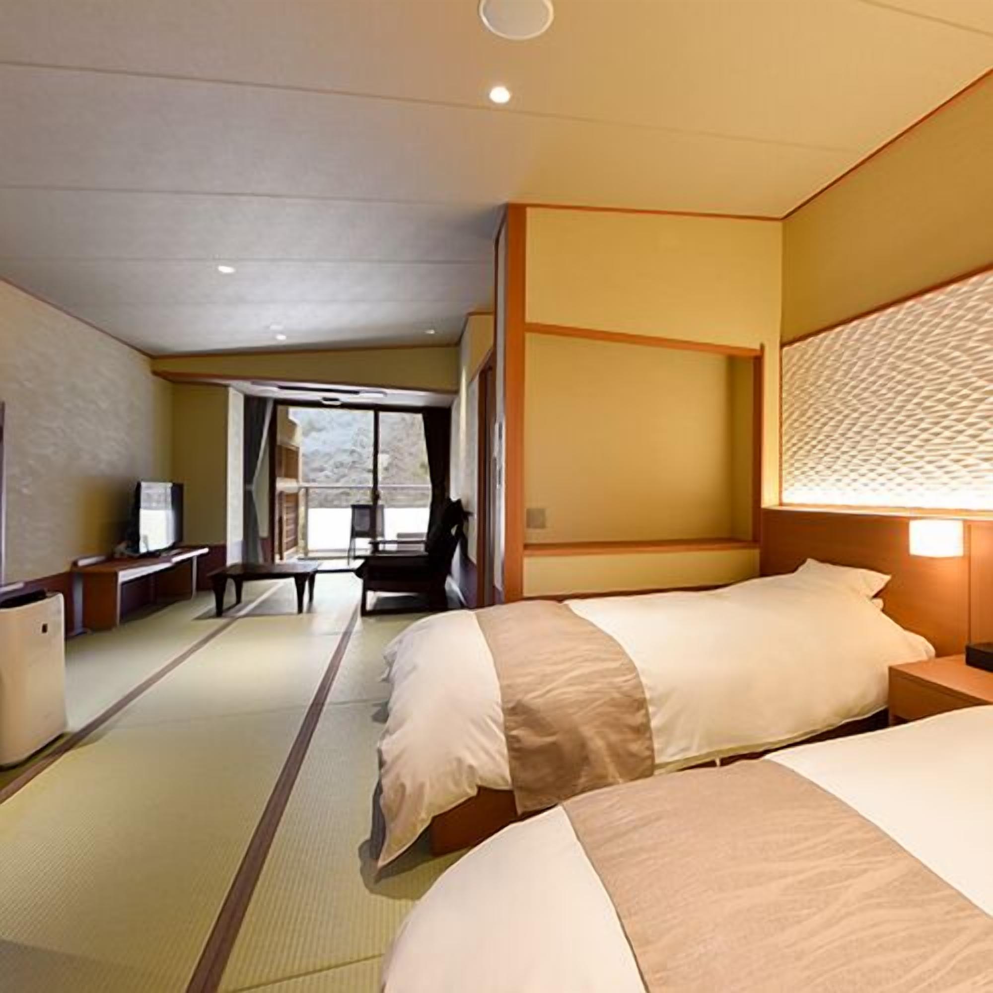 A hotel room with two beds, a desk, a chair, a television, and a view of the outdoors.
