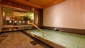 Un área de spa con un muro de azulejos, una escalera de madera y una pequeña fuente.