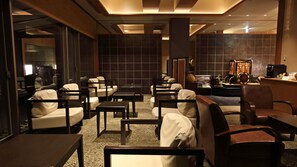 En hotellobby med sittgrupper, en receptionsdisk och en kaffemaskin.