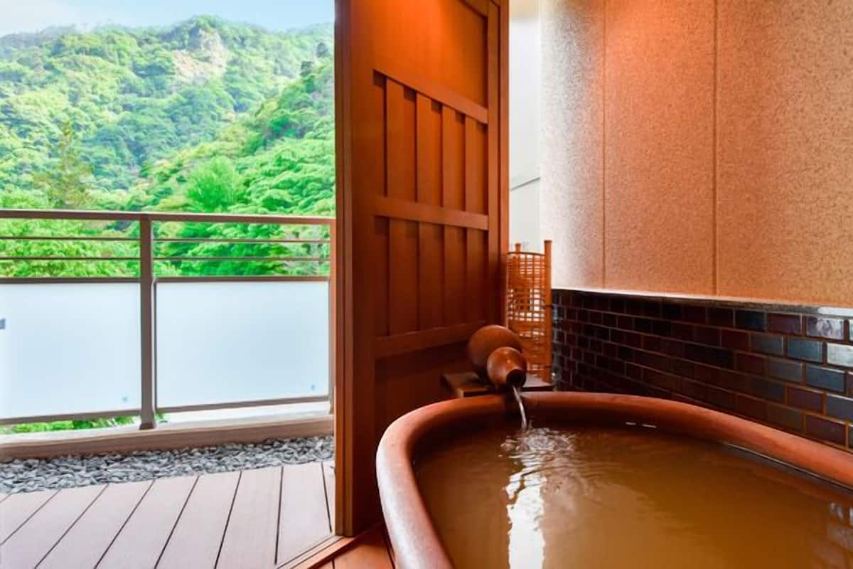 A hot tub with a wooden deck and a view of a lush green landscape.