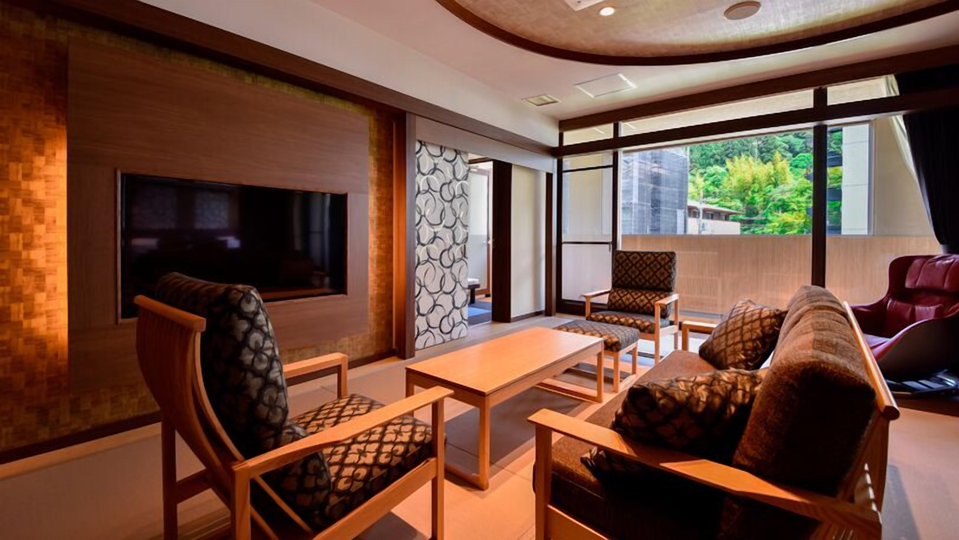 Una sala de estar moderna con televisión, asientos y vistas a zonas verdes.