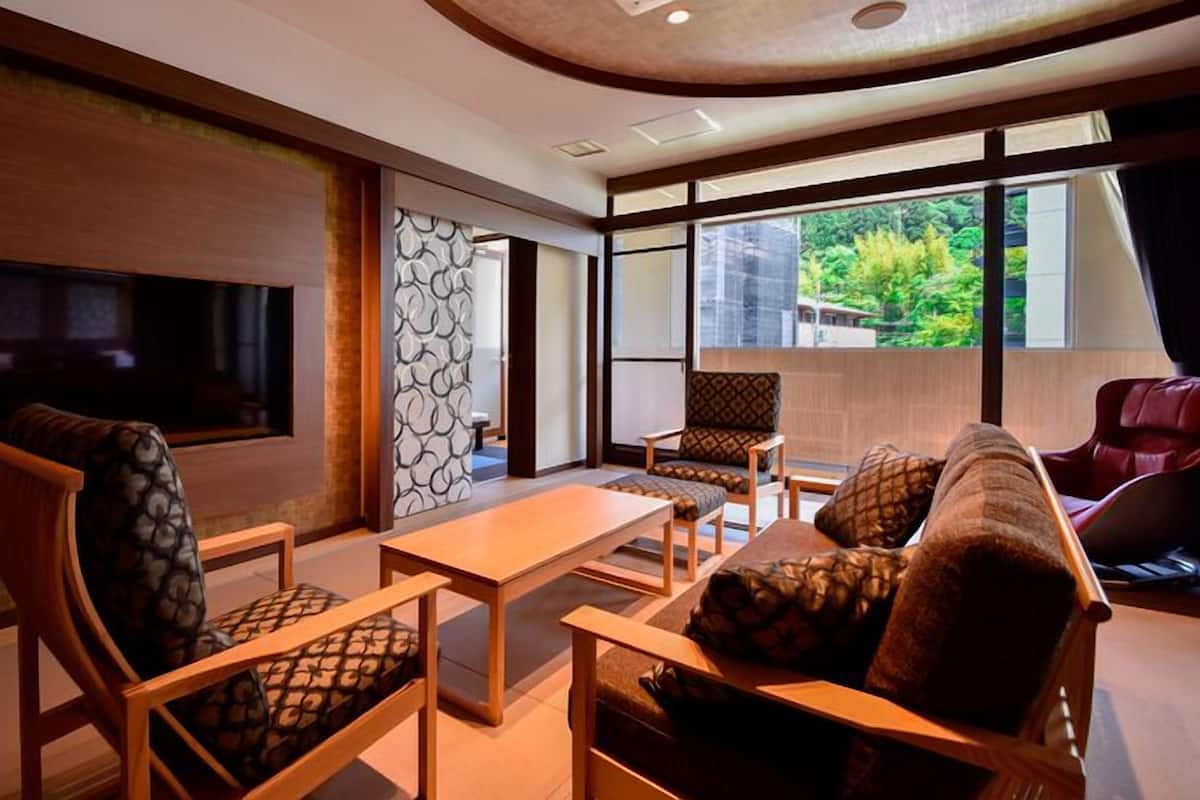 A modern living room with a TV, seating, and a view of greenery outside.