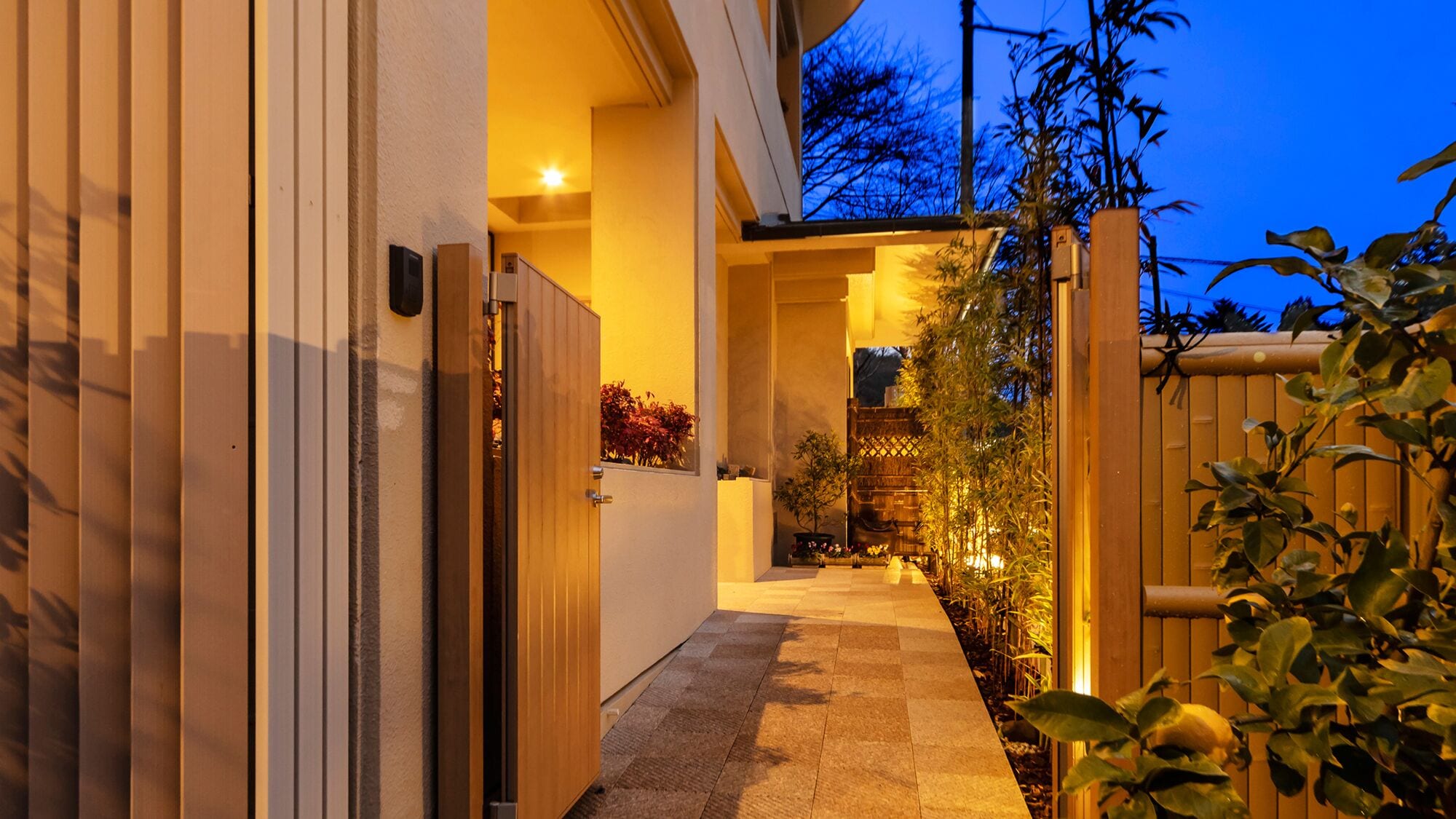 A pathway leading to a building with a wooden gate and plants.